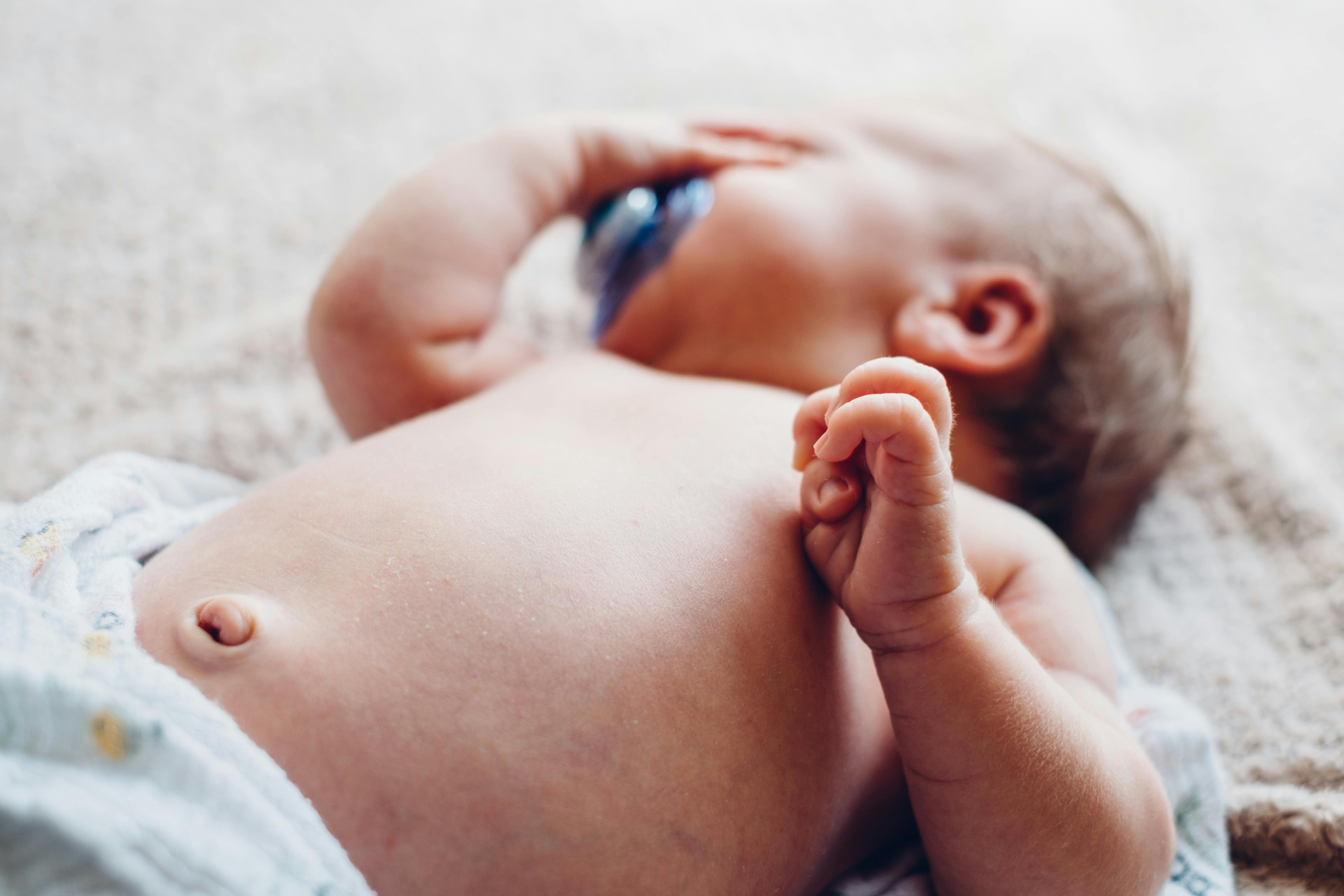 Newborn baby with pacifier lying on a blanket