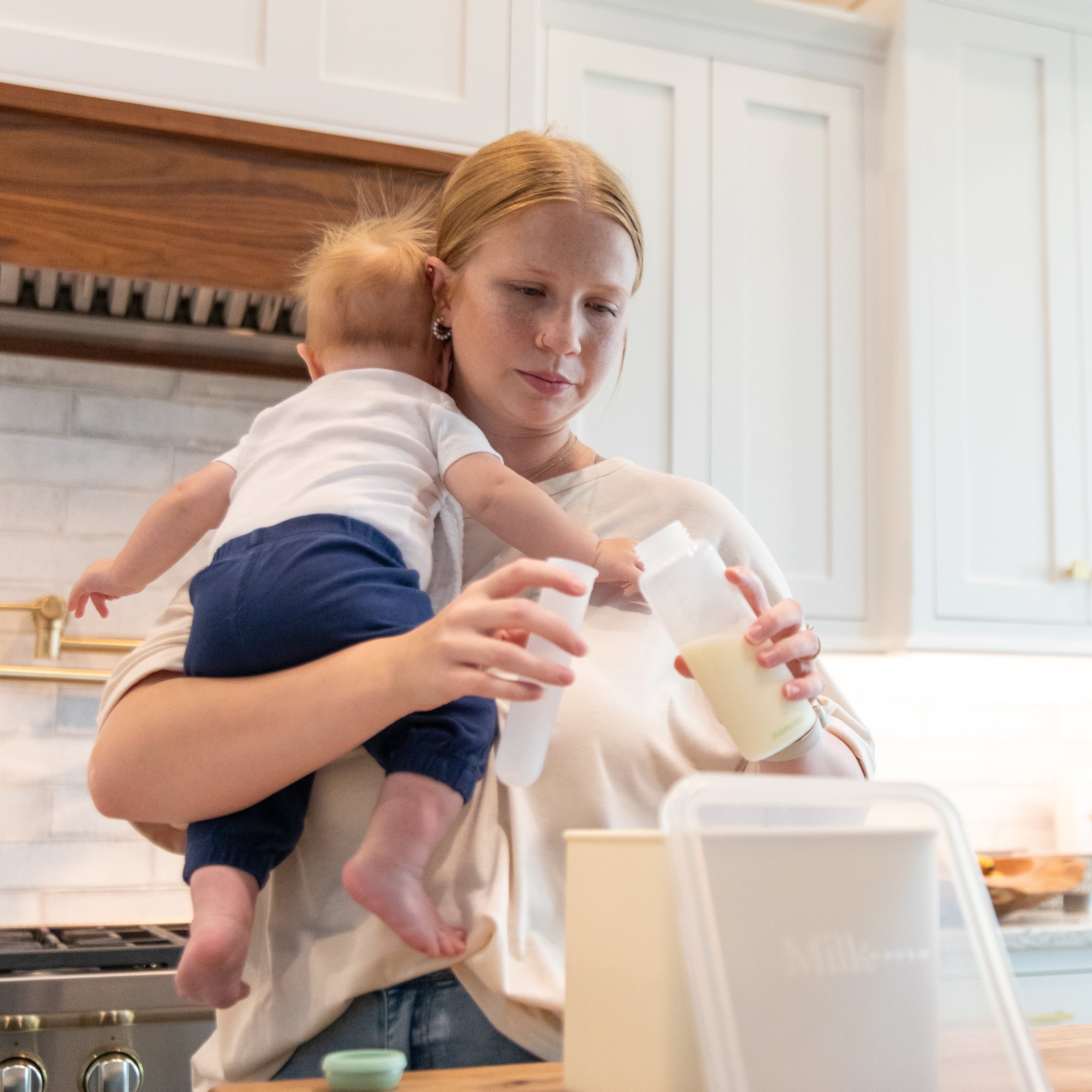 mom holding baby and pouring breastmilk into MilkHaven tube