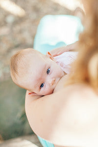 Baby being held by a person with a blurred natural background