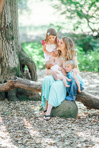 Woman sitting on a log with two children in a natural setting - lactation consultant