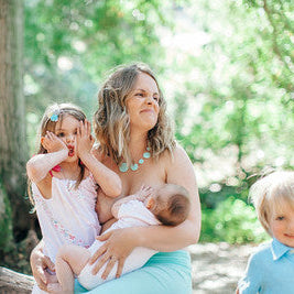 Woman sitting outdoors with two children, one holding a baby - lactation consultant near me